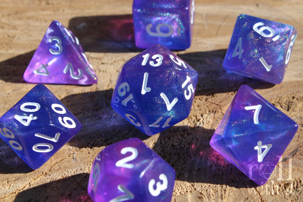 Set of glittery indigo purple polyhedral DND dice with white numbers on a wooden surface