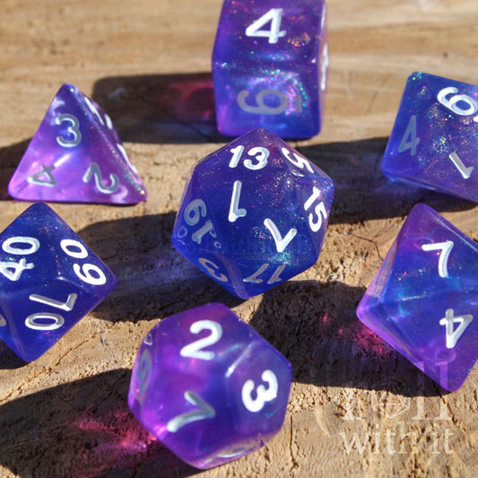 Set of 7 glittery indigo purple shiny polyhedral DND dice with white numbers on a wooden surface
