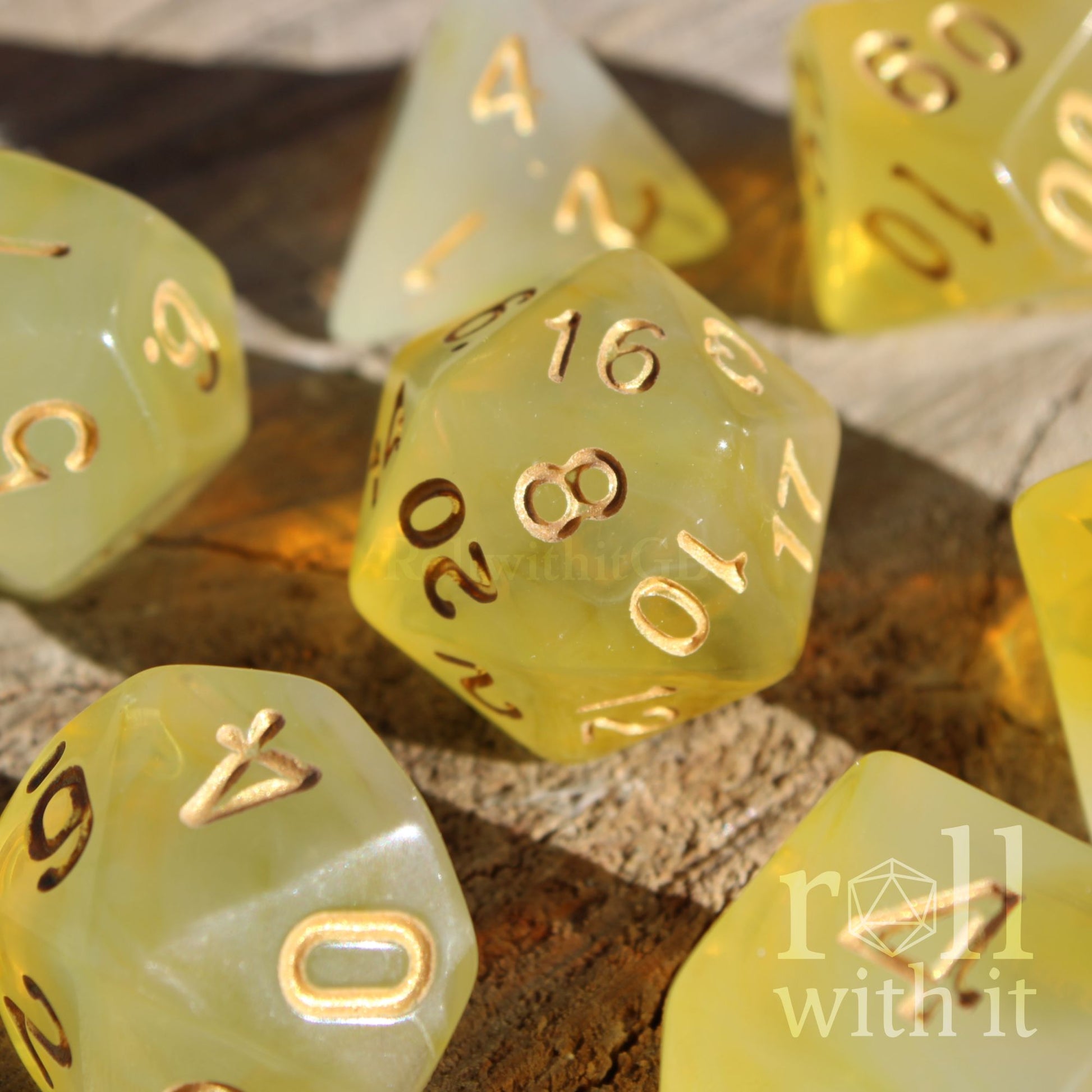 Set of 7 cute translucent lemon yellow polyhedral roleplaying tabletop dice with gold numbers on a wooden surface.