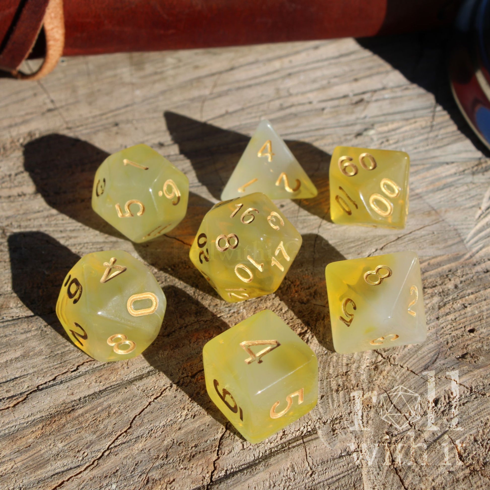 Set of 7 D&D yellow polyhedral dice on a wooden surface with golden ink numbers