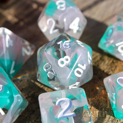 Set of light blue turquoise and white polyhedral roleplaying dice with white numbering on a wooden surface