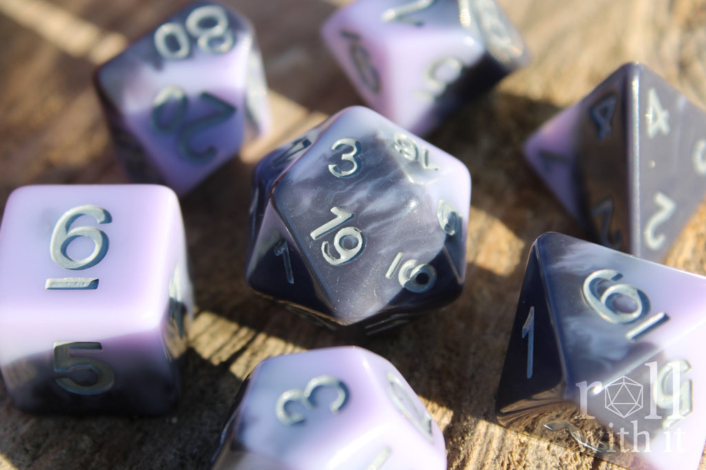 Set of pale lilac, purple and grey swirling  polyhedral roleplaying dice on a wooden surface