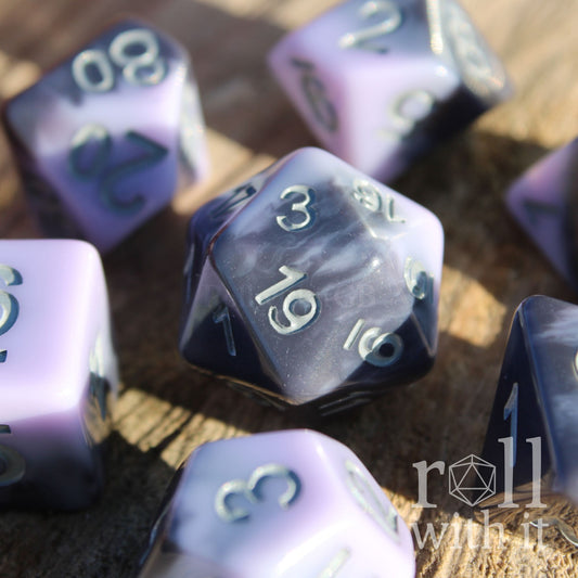 Set of pale lilac, purple and grey swirling  polyhedral roleplaying dice on a wooden surface