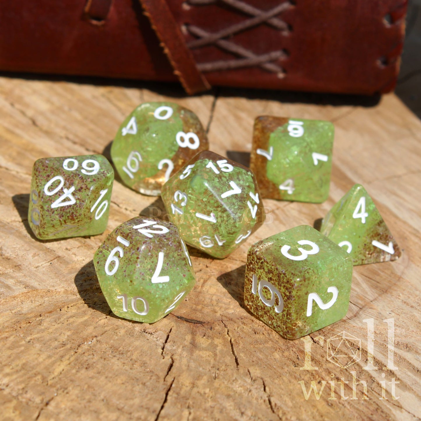 Set of green polyhedral dice with white numbers on a wooden surface