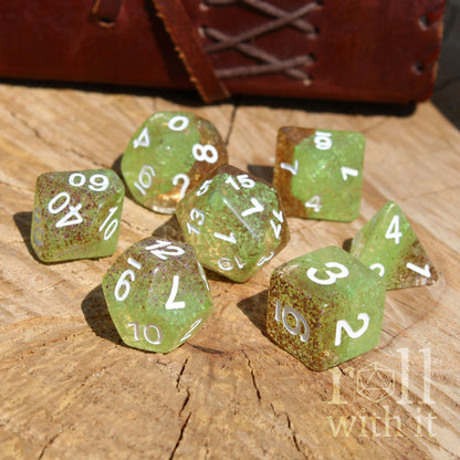 Set of green polyhedral dice with white numbers on a wooden surface