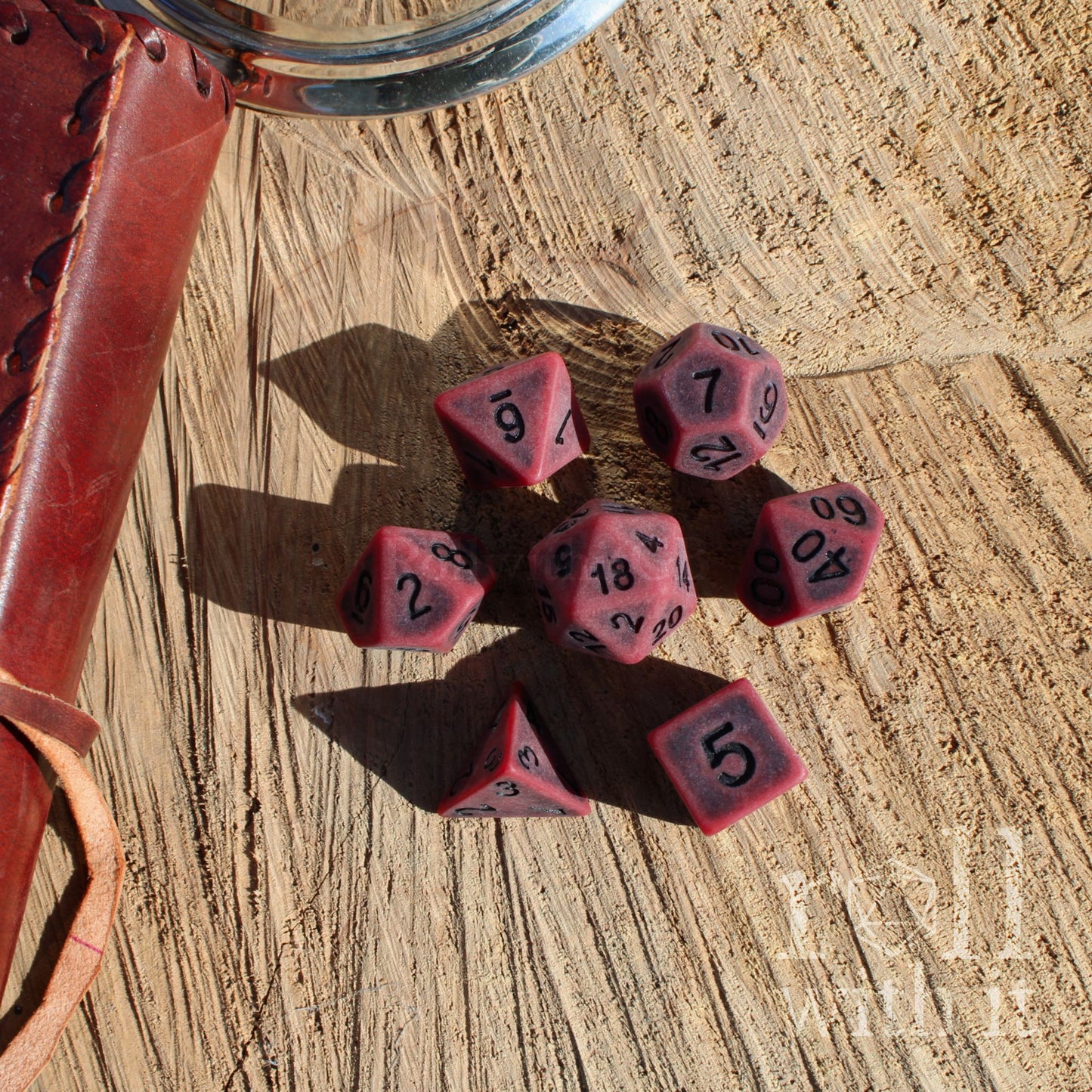 Set of red matte black number polyhedral dice with black numbers on a wooden surface