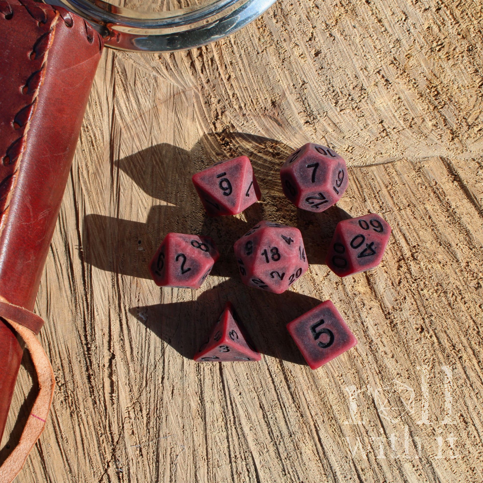 Set of red matte black number polyhedral dice with black numbers on a wooden surface