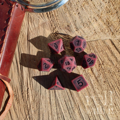 Set of red matte black number polyhedral dice with black numbers on a wooden surface