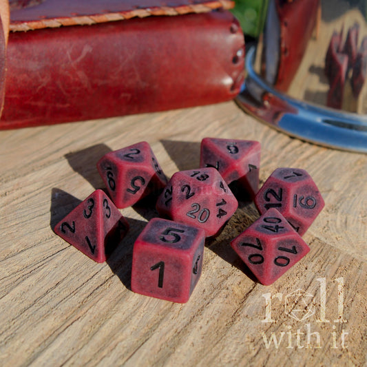 Set of red matte polyhedral dice on a wooden surface with 'roll with it' text.