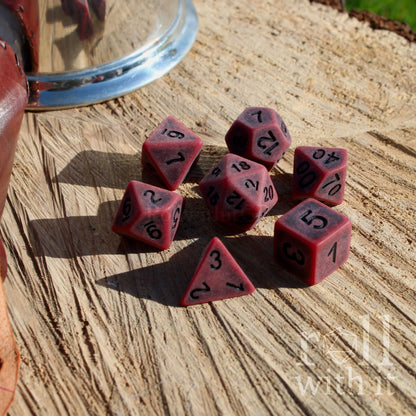 Red matte polyhedral dice set on a wooden surface with 'roll with it' branding.