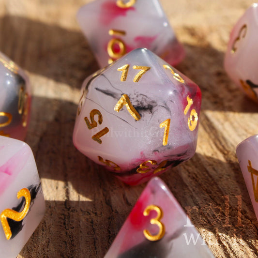 Set of black, red, and creamy white roleplaying dice with marbled design and gold numbers on a wooden surface