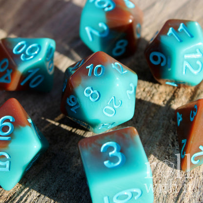Set of turquoise blue and chocolate brown polyhedral roleplaying dice on a wooden surface