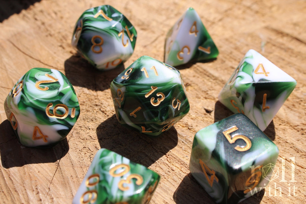 Set of green and white swirling polyhedral DND dice with gold numbers on a wooden surface