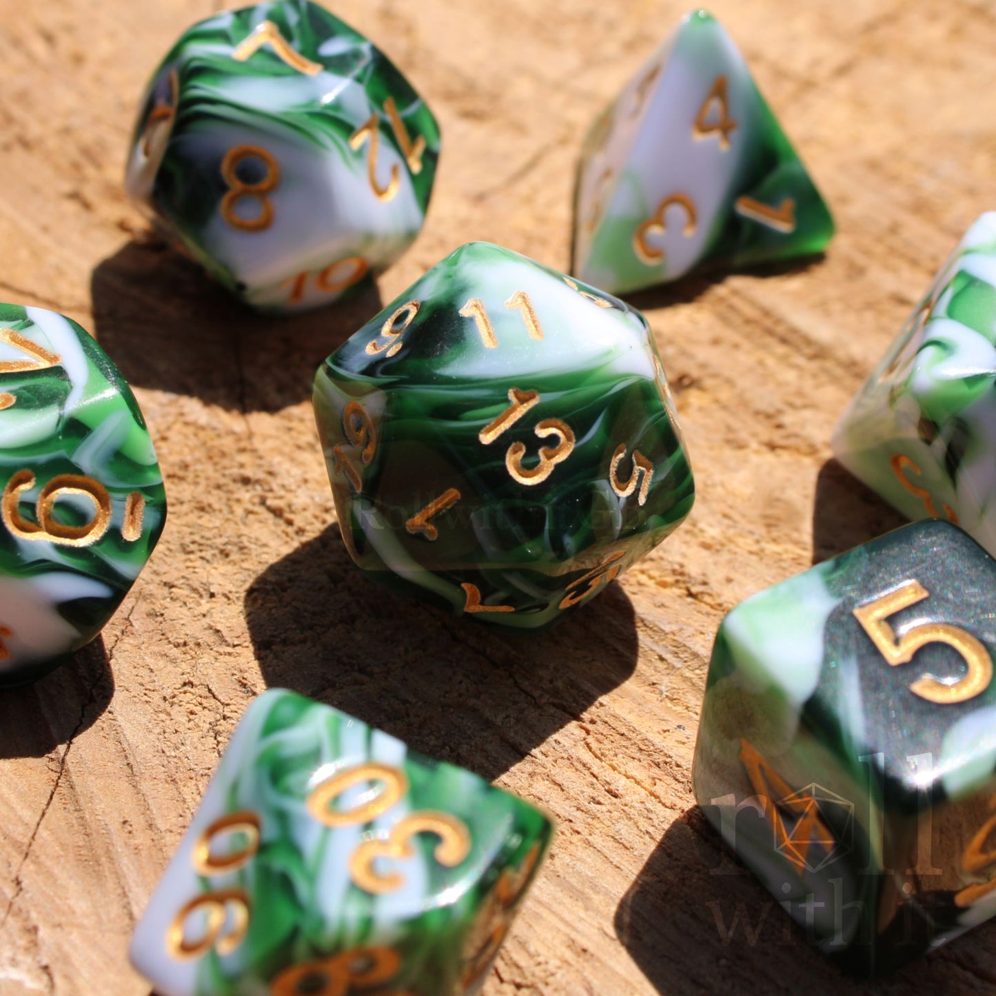 Set of green and white swirling polyhedral DND dice with gold numbers on a wooden surface