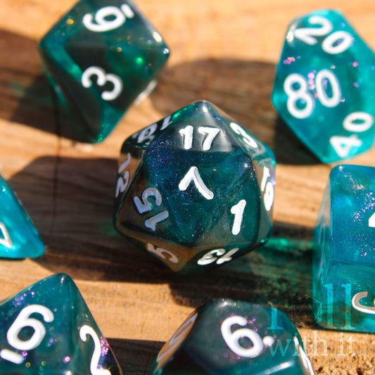 Teal and black glittery polyhedral roleplaying dice set with white numbers on a wooden surface