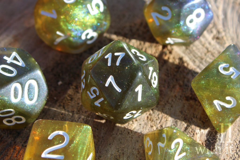 Set of green olive and blue polyhedral dice with white numbers on a wooden surface.