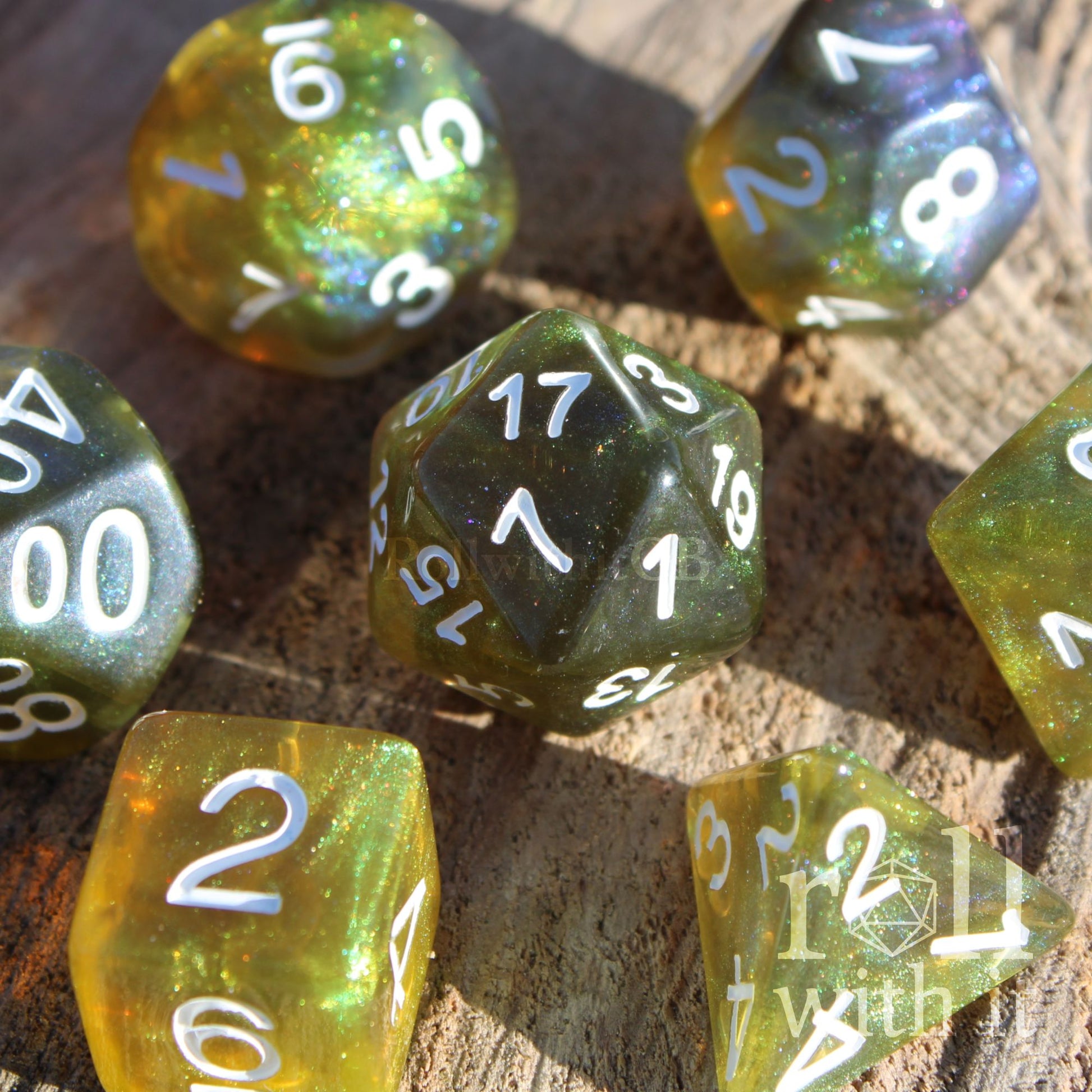 Set of green olive glitter and blue polyhedral dice with white numbers on a wooden surface.