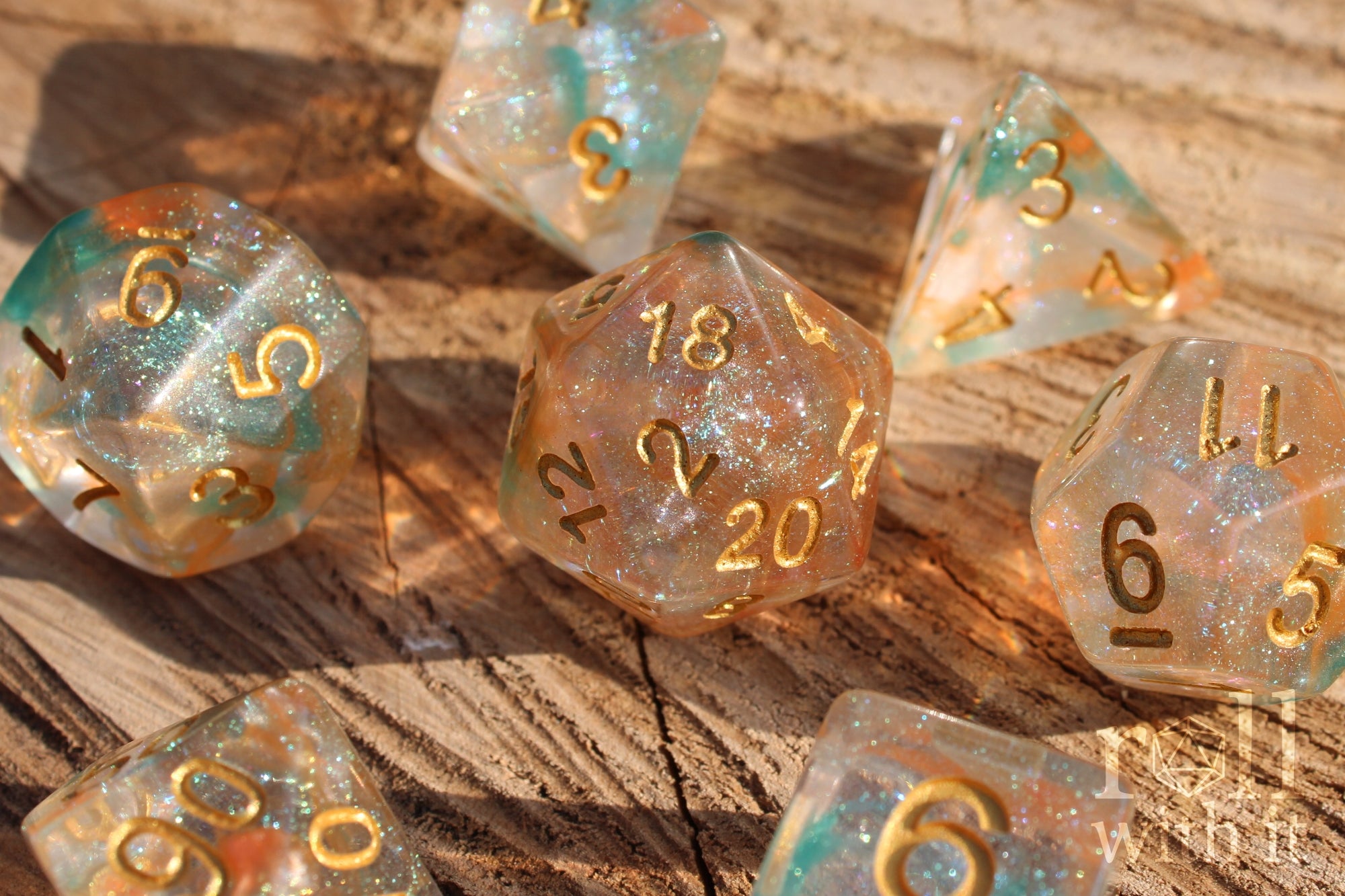 A set of bright glitter filled orange and green polyhedral roleplaying dice with gold numbers on a wooden oak surface