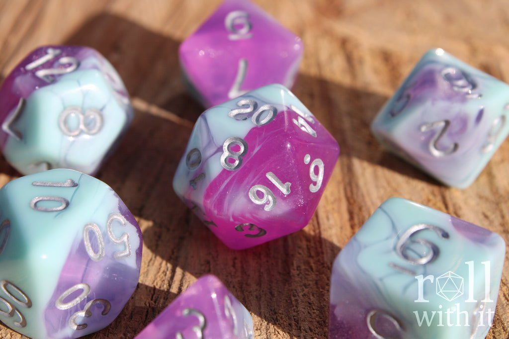 Set of 7 pastel blue marble and clear orchid purple polyhedral DND roleplaying dice on a wooden surface