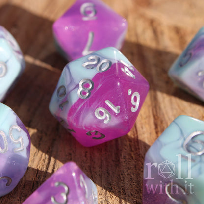 Set of 7 pastel blue marble and clear orchid purple polyhedral DND roleplaying dice on a wooden surface