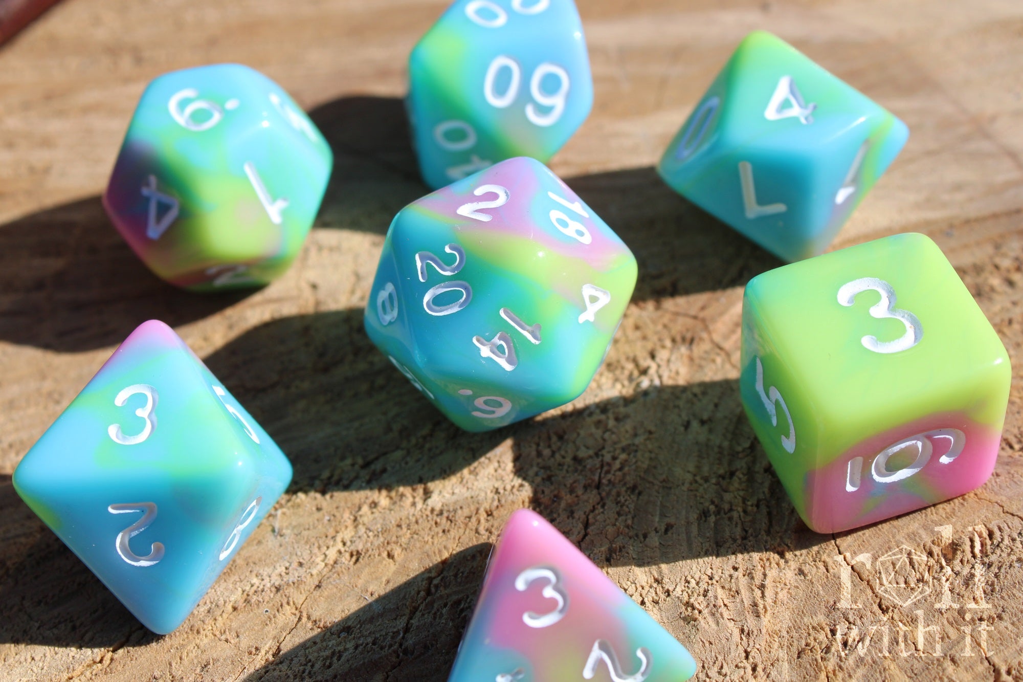 Set of colourful pastel rainbow polyhedral roleplaying dice with white numbering on a wooden surface