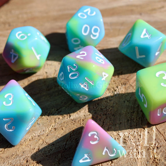 Set of 7 cute colourful pastel rainbow polyhedral roleplaying dice with white numbering on a wooden surface