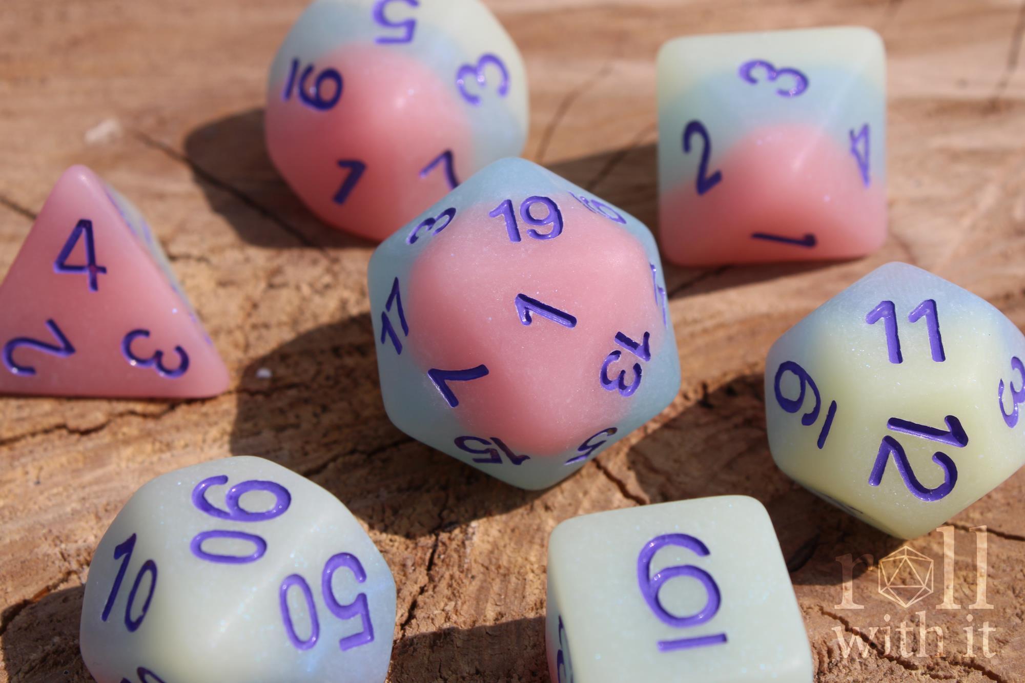 Set of pastel polyhedral roleplaying dice with numbers on a wooden surface