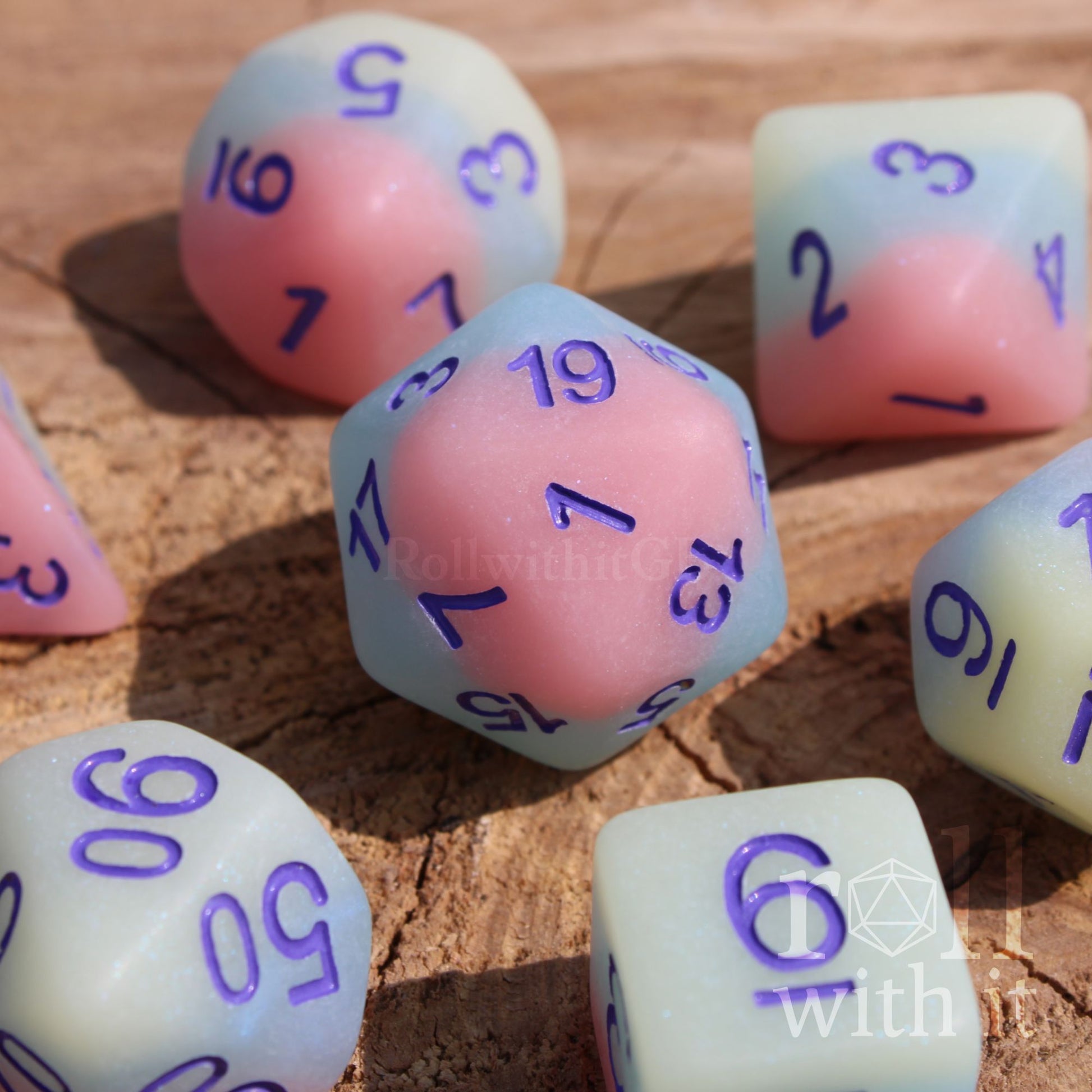 Set of pastel polyhedral roleplaying dice with numbers on a wooden surface