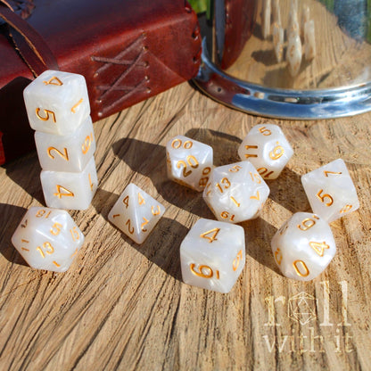 Set of 11 white and blue swirling roleplaying dice with gold numbers on a wooden surface
