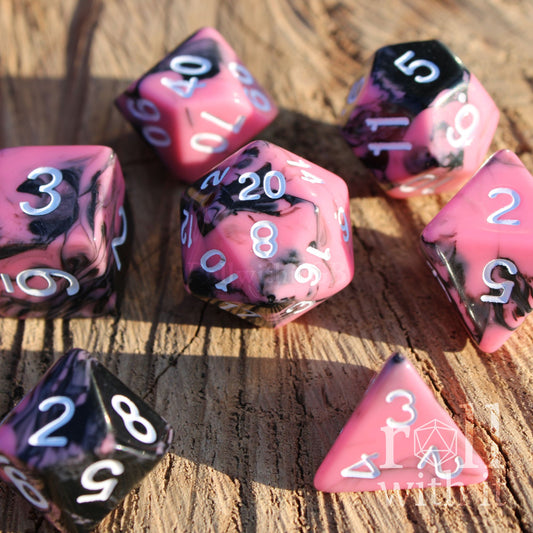 Set of 7 pink and black swirling polyhedral roleplaying dice on a wooden surface