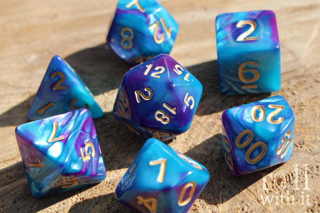 A set of colorful purple and blue polyhedral dice with golden numbers on a wooden surface