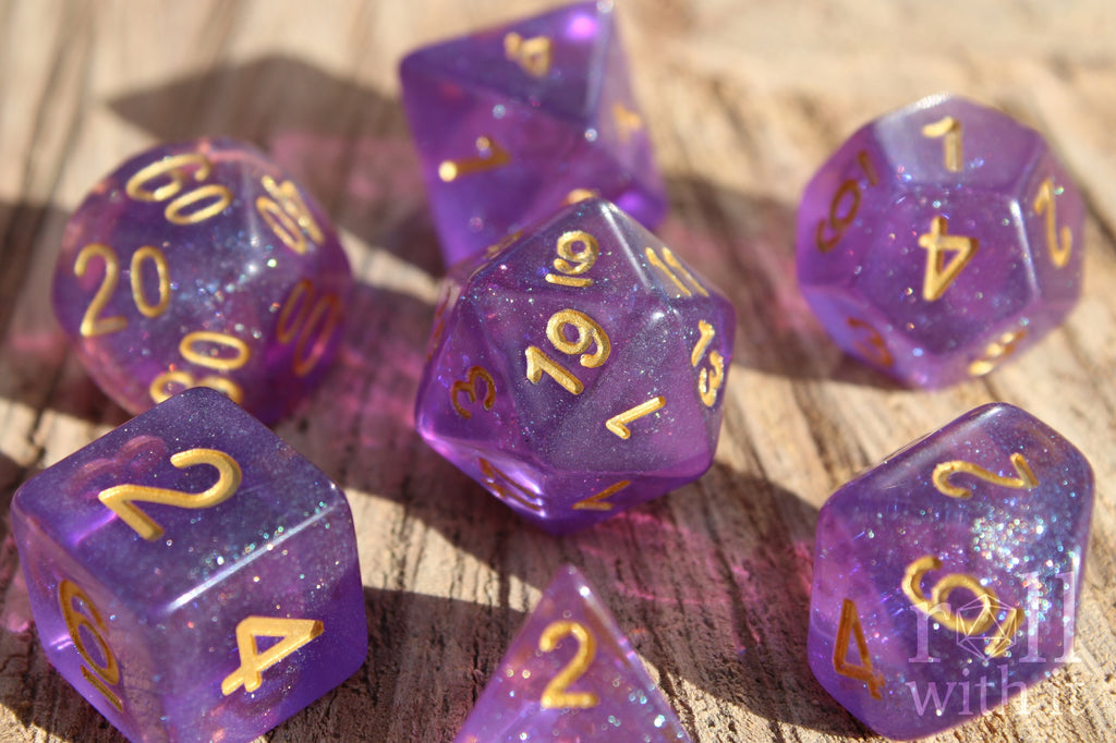 Set of glittery purple polyhedral DND dice with gold numbers on a wooden surface