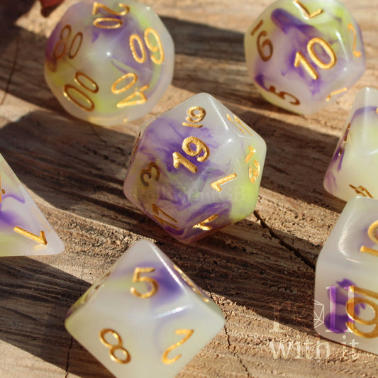 Set of purple green and creamy white dice with gold numbers on a wooden surface