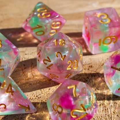 Set of 7 purple green glitter clear dice on a wooden surface