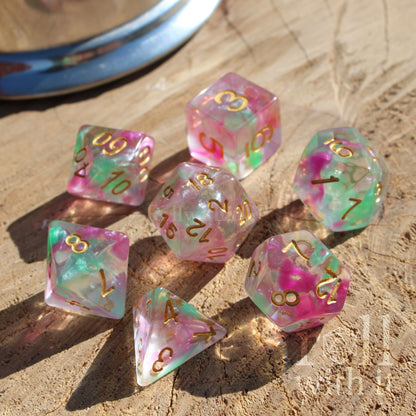 Set of colorful clear dnd purple green gold letters polyhedral dice on a wooden surface
