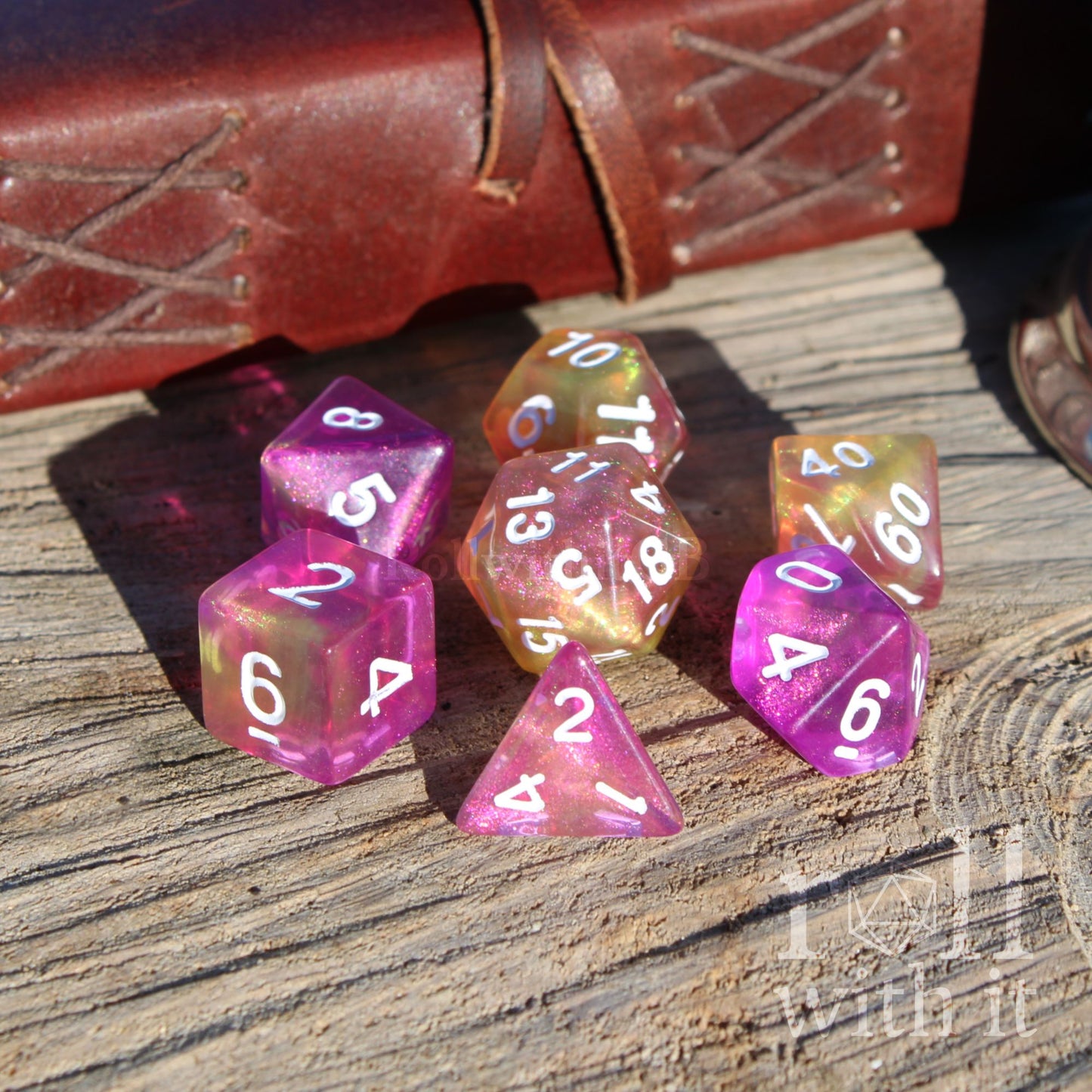 Set of colorful polyhedral dice on a wooden surface with leather-bound book in the background