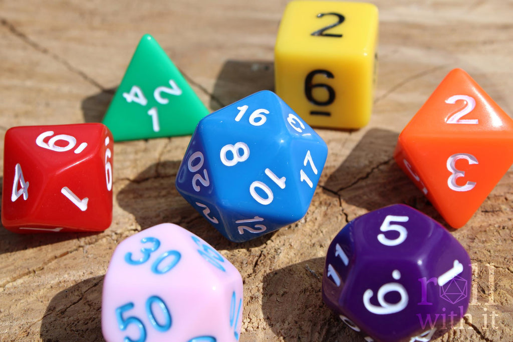A colourful set of rainbow polyhedral roleplaying dice with white, blue, and black numbers on a wooden surface