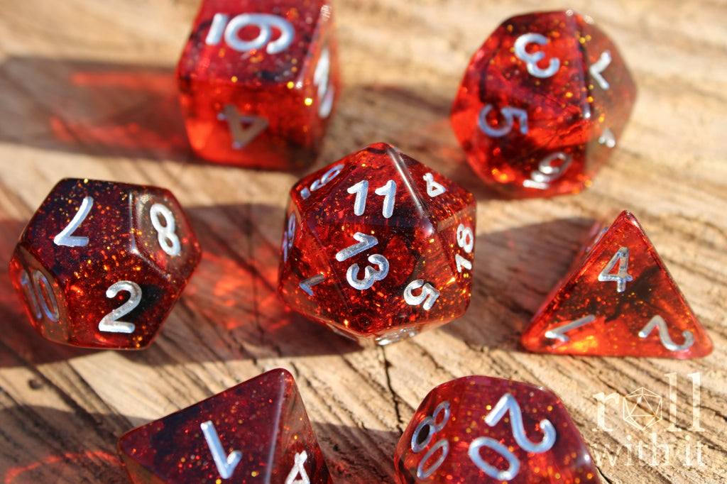 Set of red and black glittery polyhedral roleplaying dice with silver numbers on a wooden surface