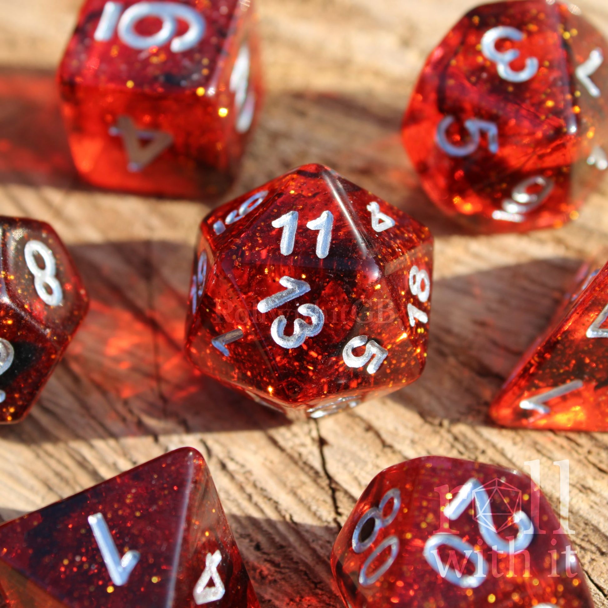 Set of red and black glittery polyhedral roleplaying dice with silver numbers on a wooden surface