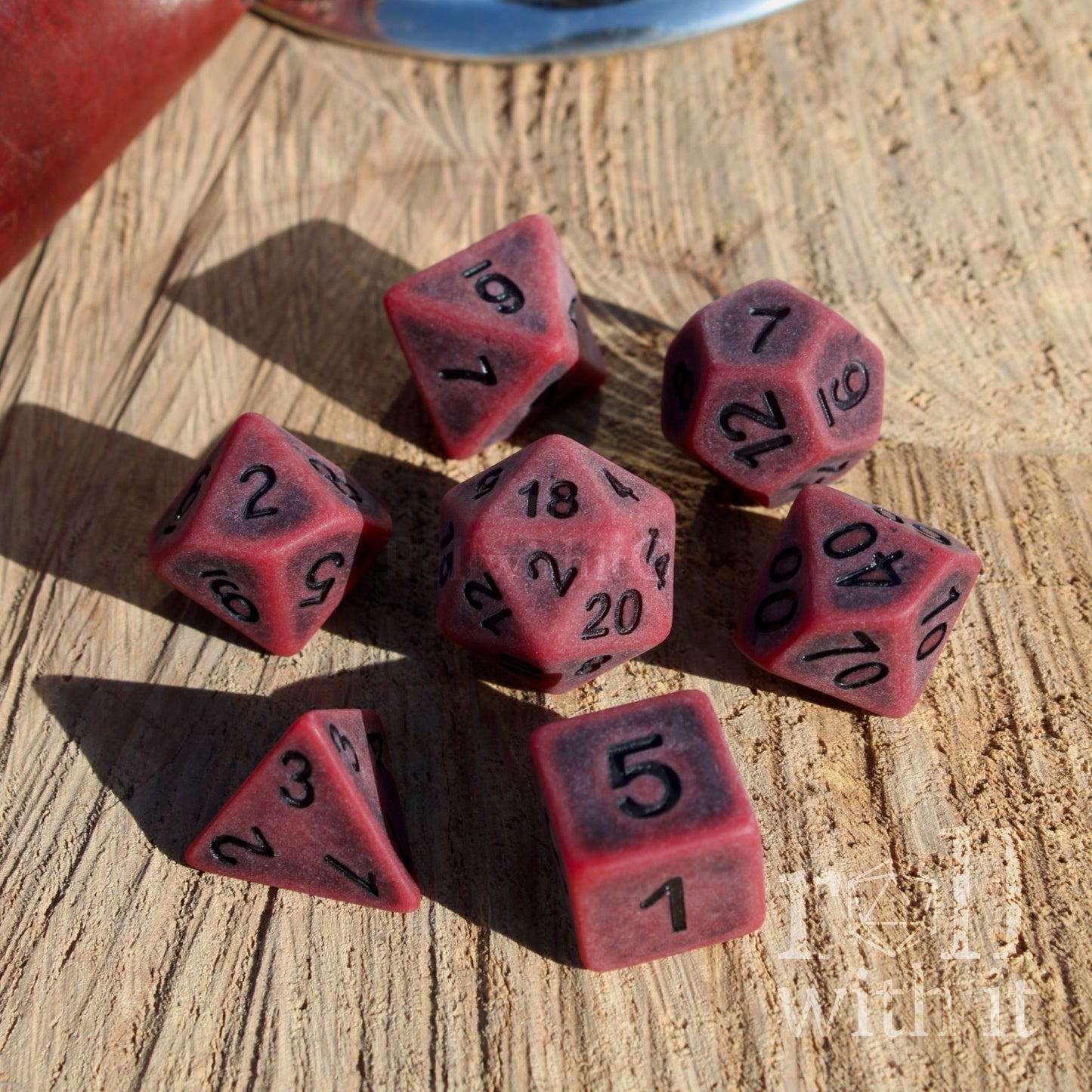Set of red matte polyhedral dice with black numbers on a wooden surface