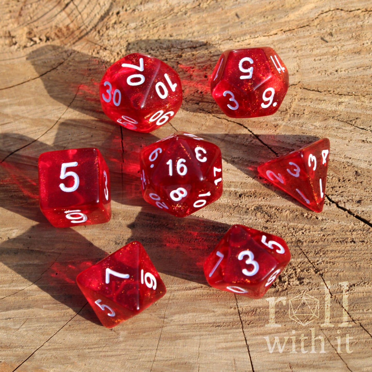 7 bright shimmering shiny red dice dnd TTRPG set on a wooden surface with 'roll with it' text.
