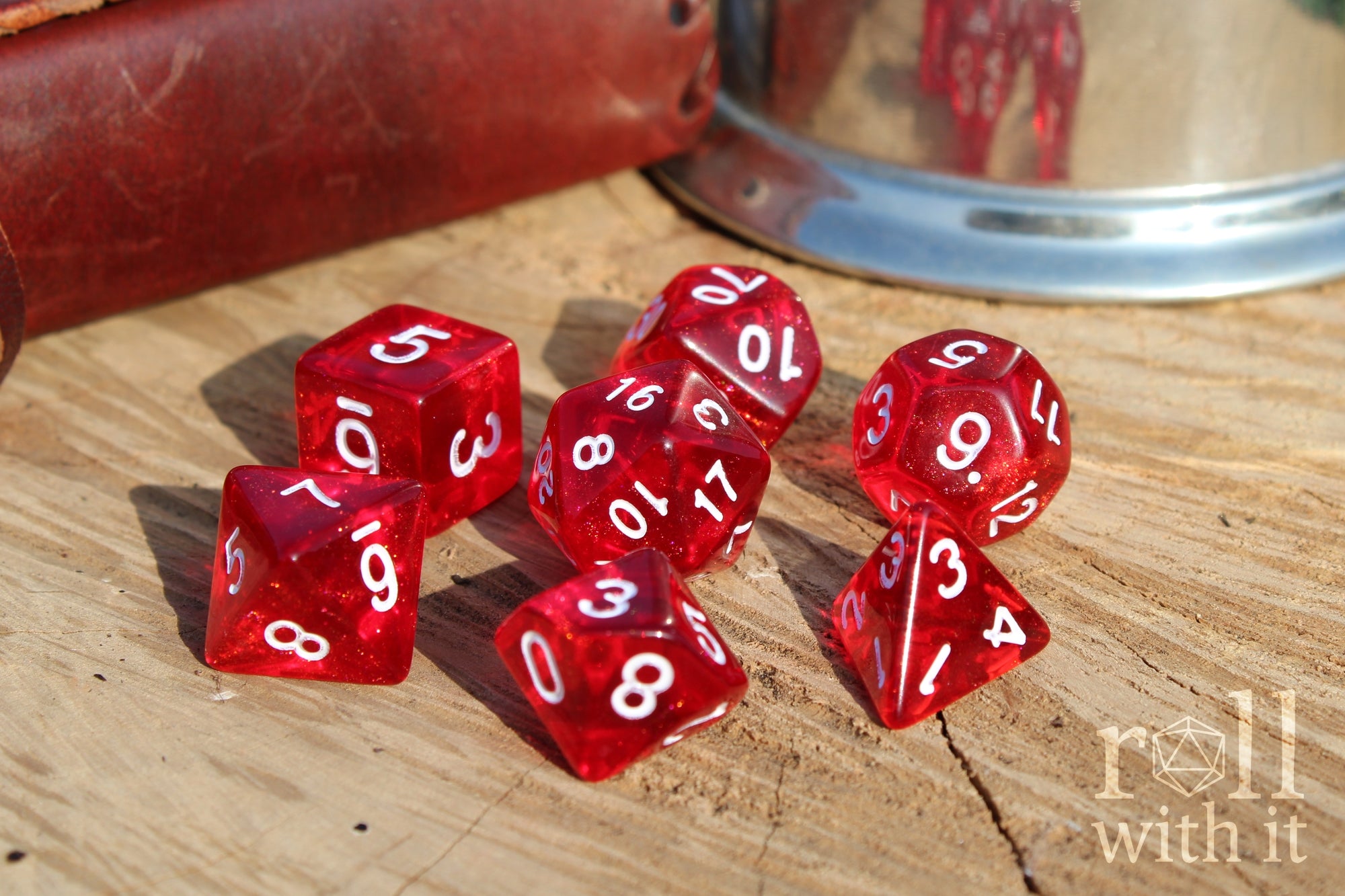 Scarlet red glittery polyhedral roleplaying dice with white numbers on a surface