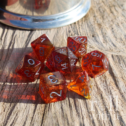 Set of shiny red and orange polyhedral dice on a wooden surface