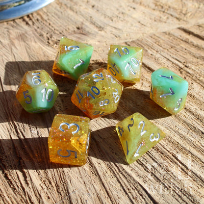 Set of colorful polyhedral dungeons and dragons dice with gold foil and silver numbers on a wooden surface