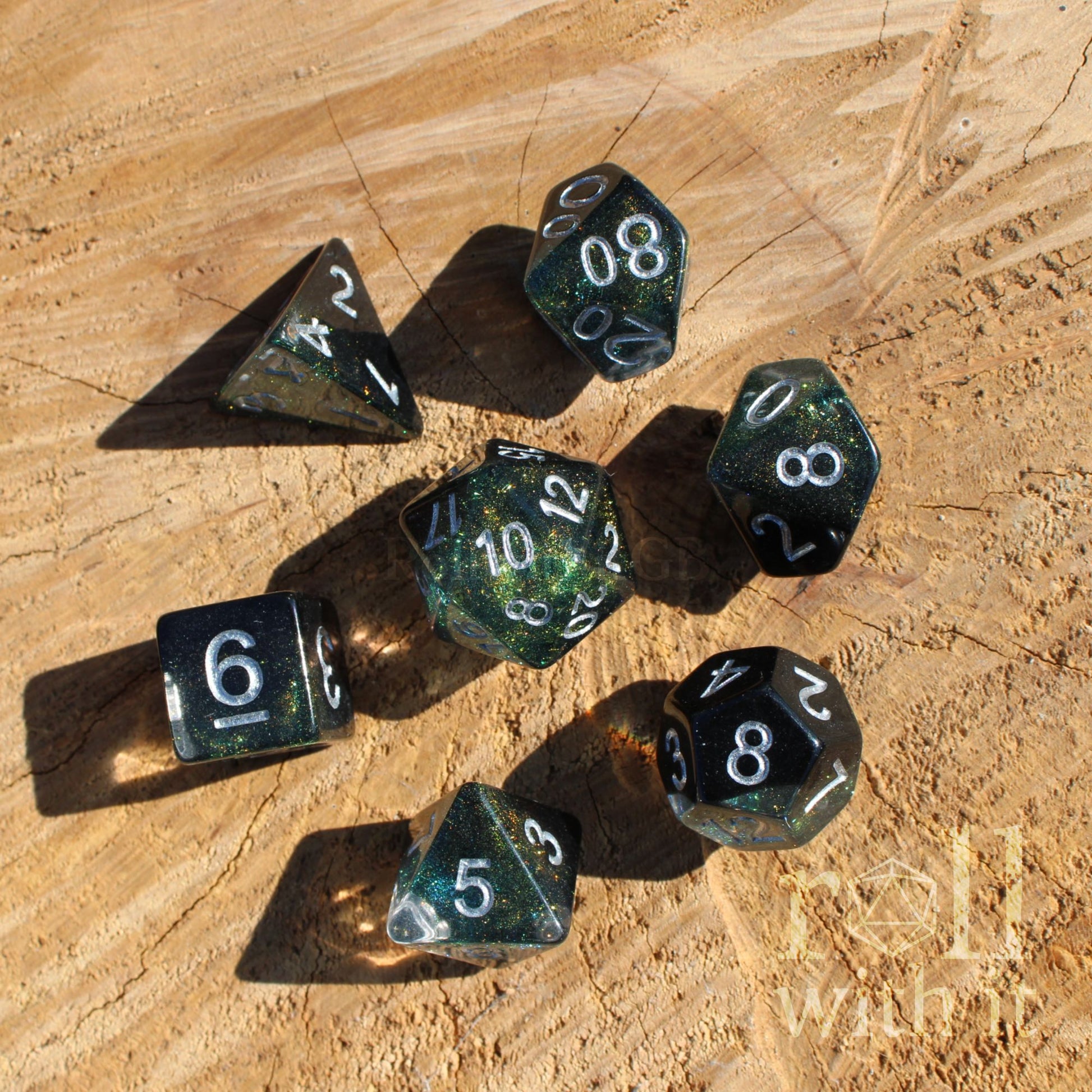 Set of green black clear polyhedral dice  with silver numbers on a wooden surface