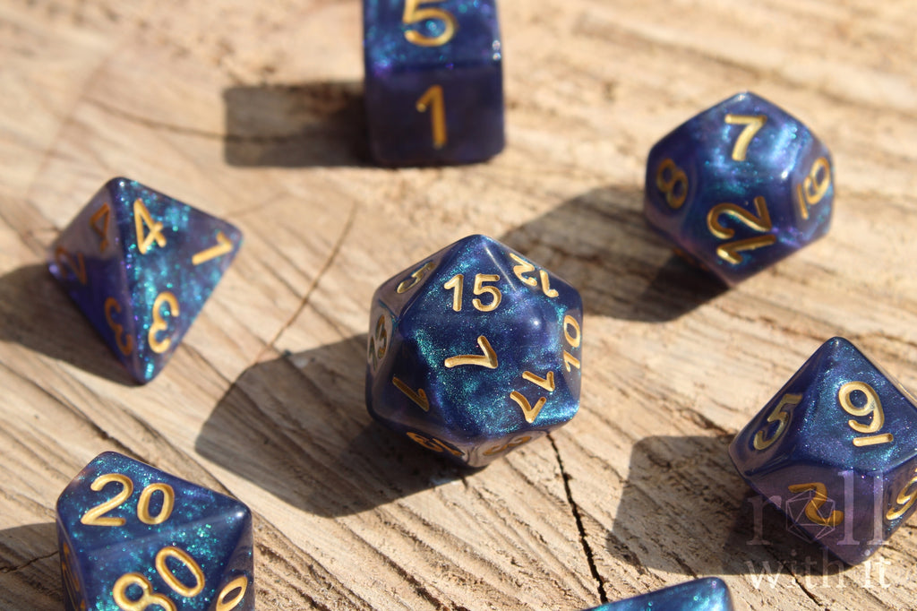 Deep blue and glittery polyhedral roleplaying dice with gold numbers on a wooden surface