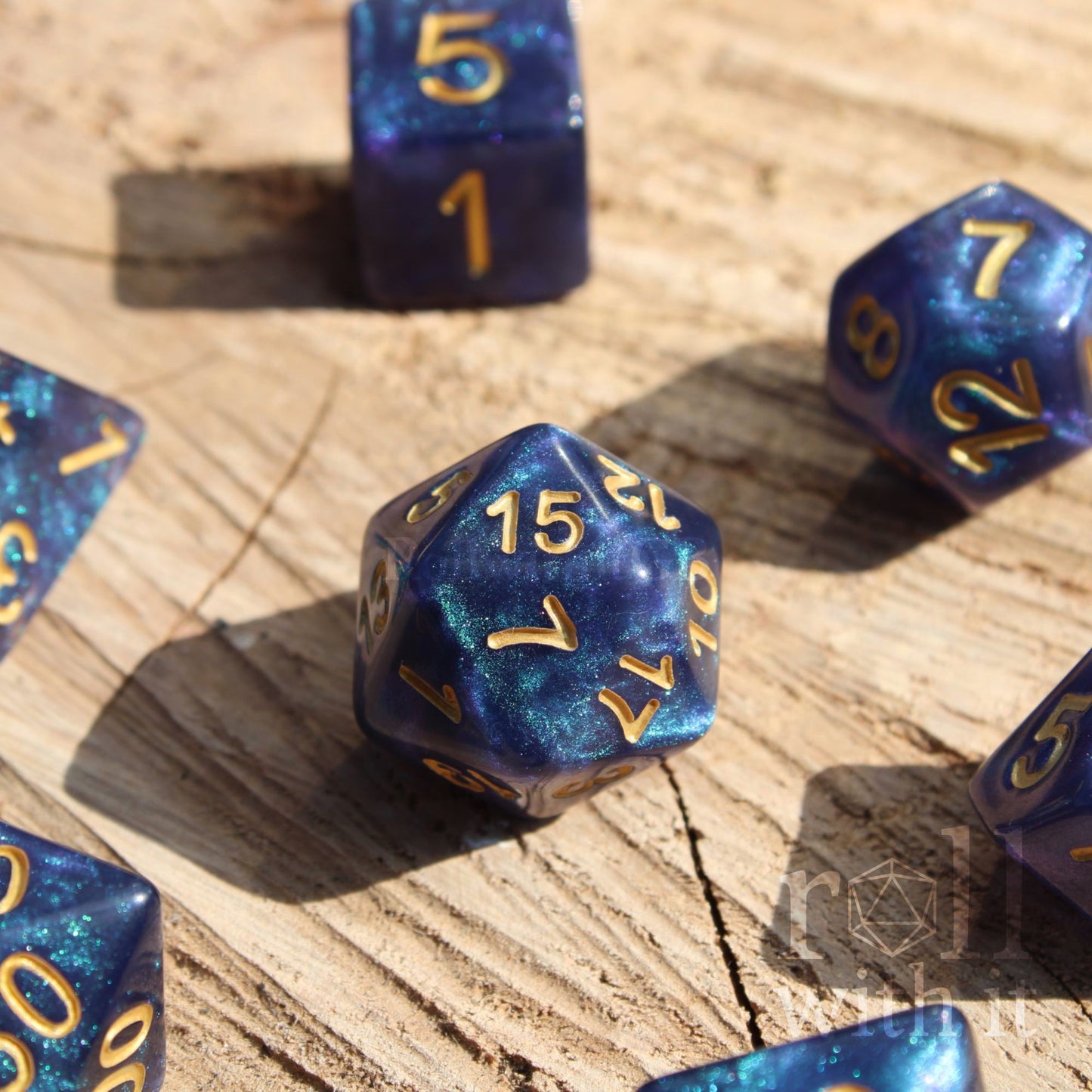 Deep blue and glittery polyhedral roleplaying dice with gold numbers on a wooden surface