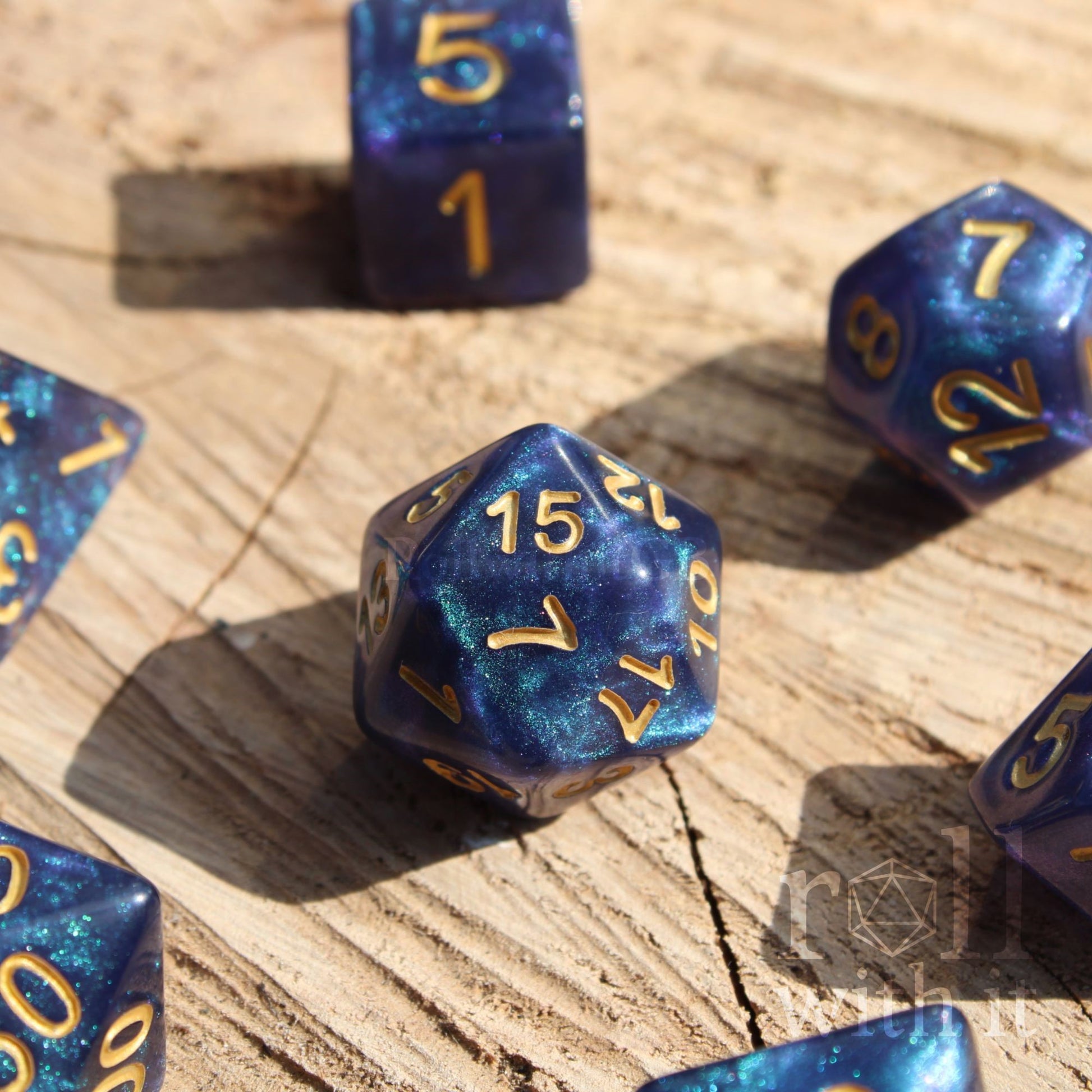 Deep blue and glittery polyhedral roleplaying dice with gold numbers on a wooden surface