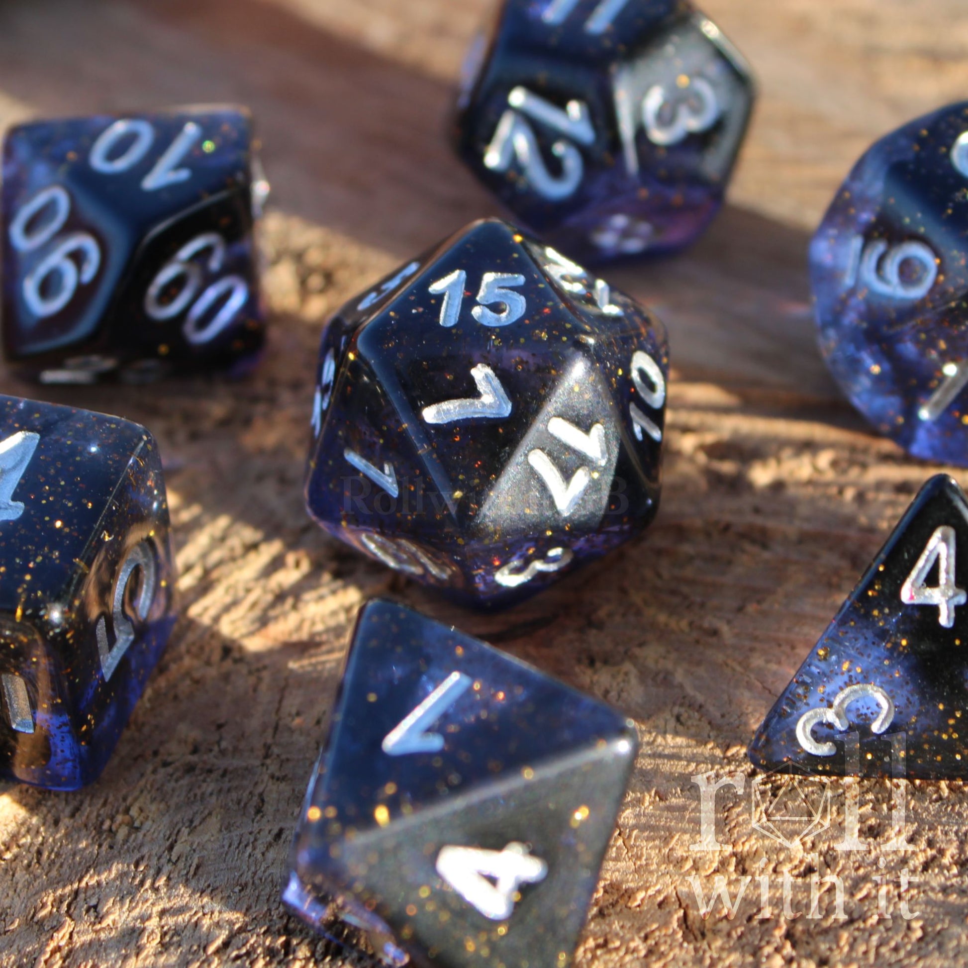 Set of deep blue-black polyhedral role-playing dice with gold flecks on a wooden surface