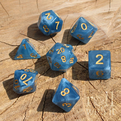 Blue swirling jade polyhedral dice with gold numbers on a wooden surface